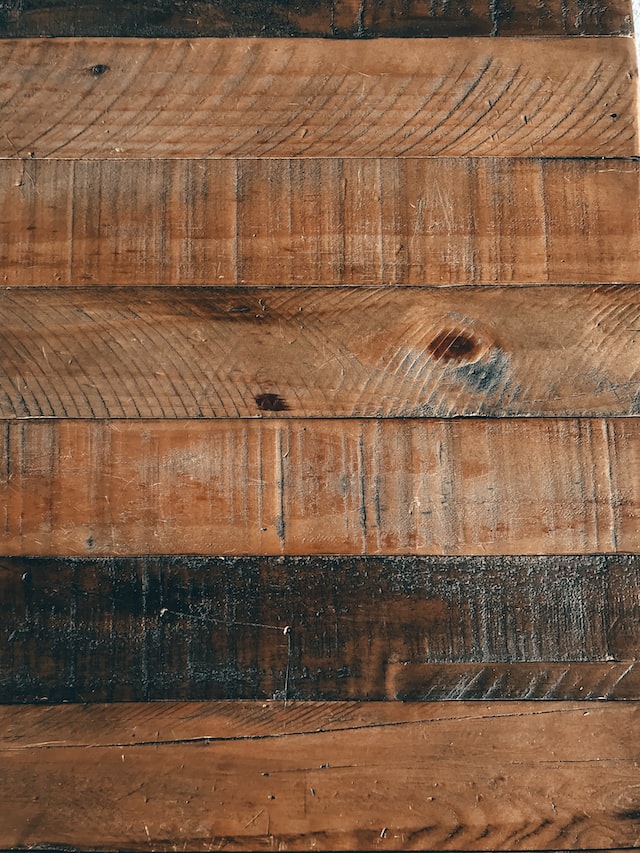 Six wood floor boards, the fifth board down is darker than the others