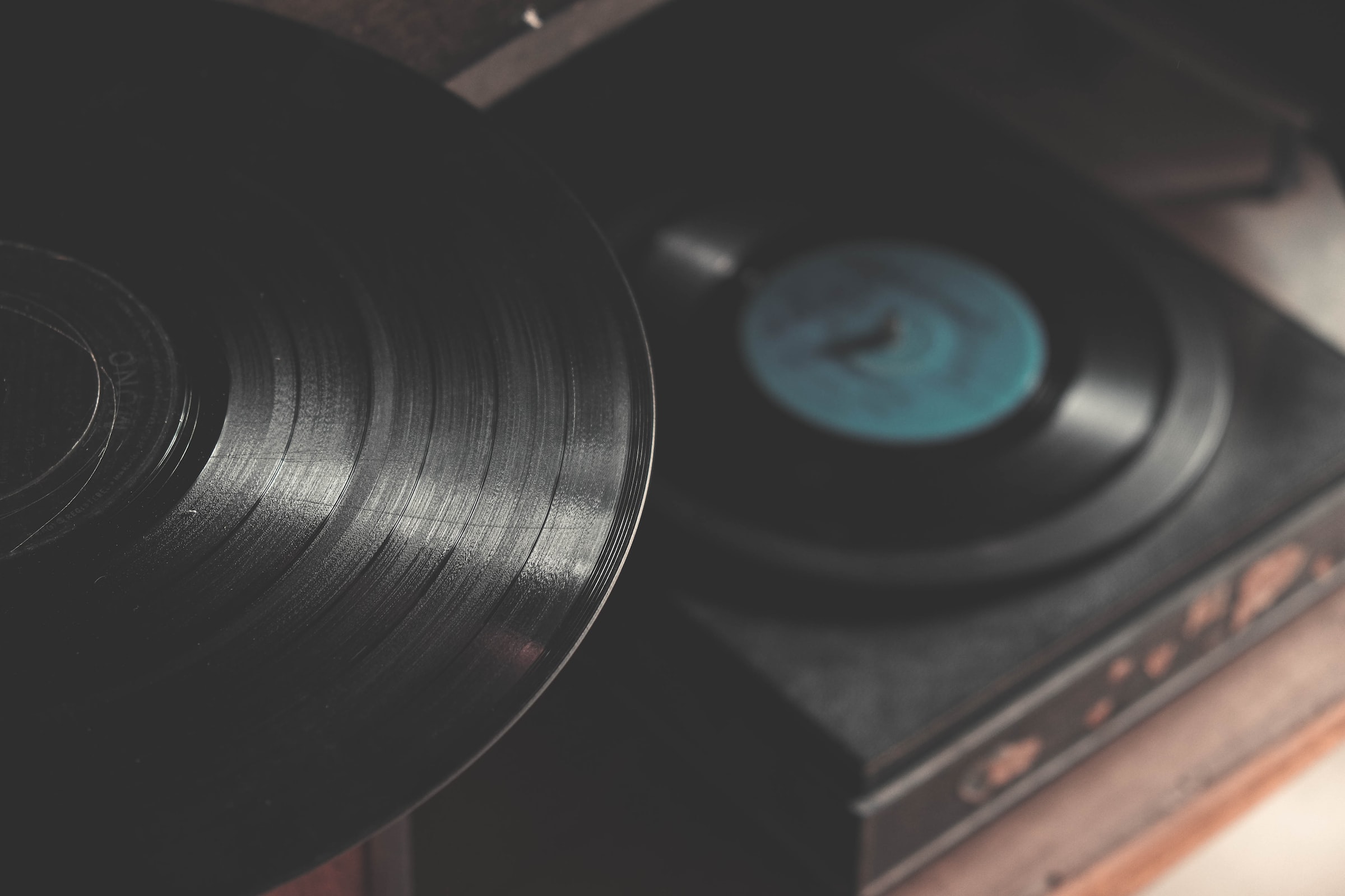 A vinyl record on a shelf; in the background another record sits on a turntable